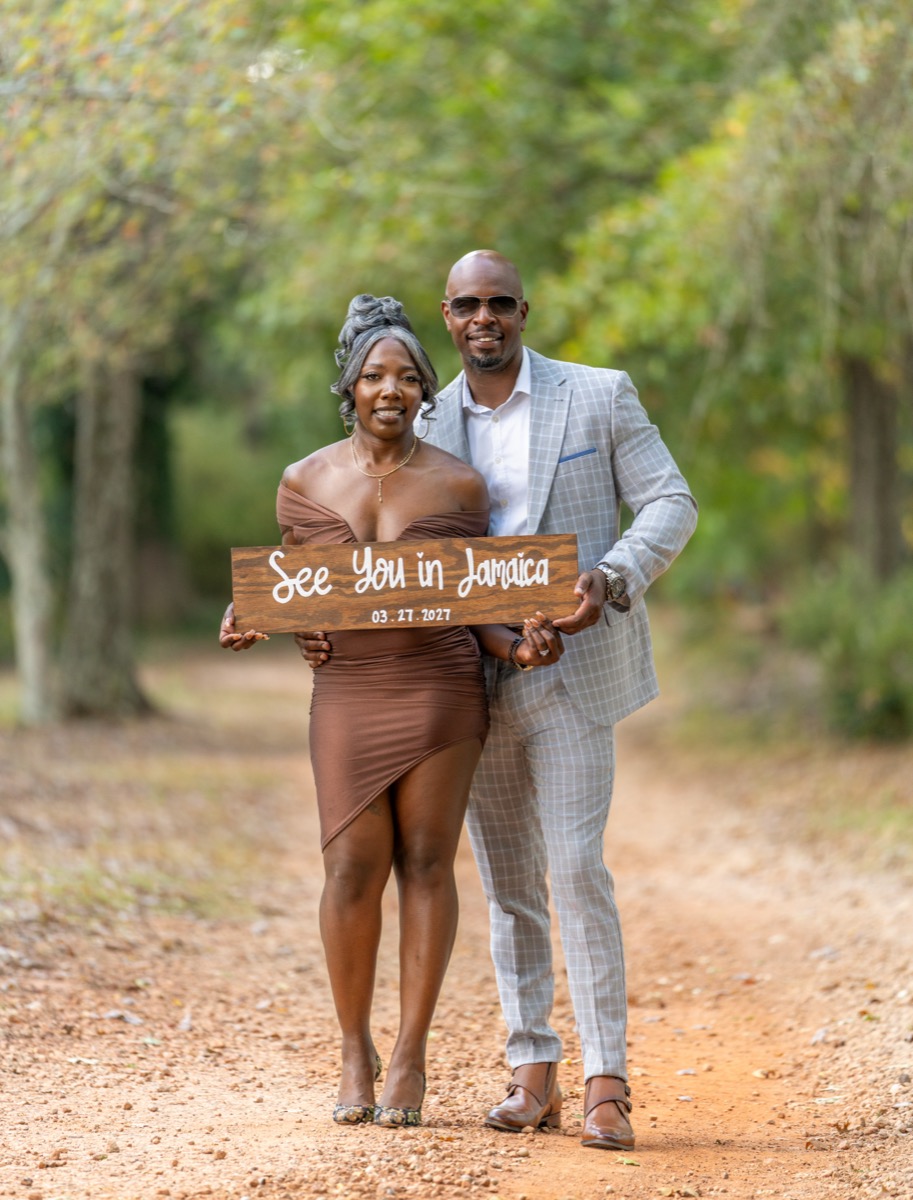 Dwayne and Samantha holding a See You in Jamaica sign